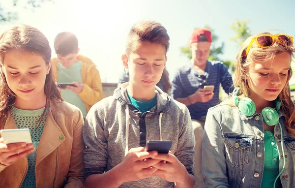 Grupo de amigos adolescentes con teléfonos inteligentes al aire libre — Foto de Stock