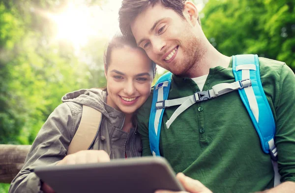 Gelukkige paar met rugzakken en tablet pc buitenshuis — Stockfoto