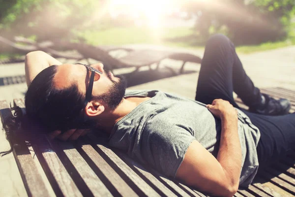 Homem feliz deitado no banco de rua ou na cama de sol — Fotografia de Stock