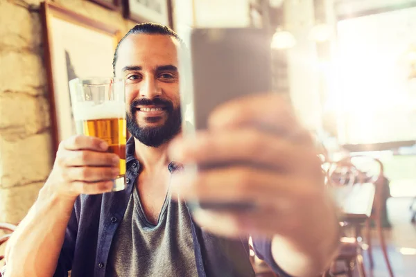 Человек со смартфоном пьет пиво в баре или пабе — стоковое фото