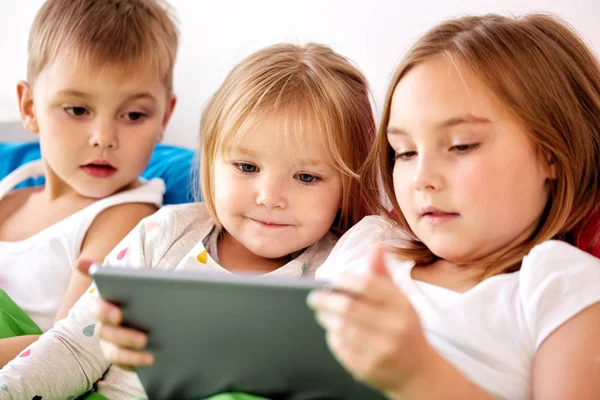 Małe dzieci z komputera typu tablet w łóżku w domu — Zdjęcie stockowe