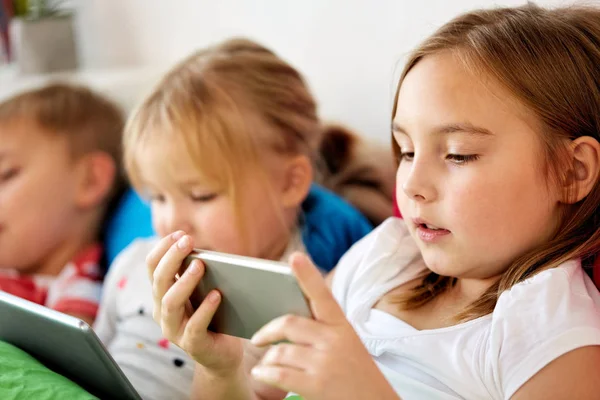 Little kids with smartphone in bed at home — Stock Photo, Image