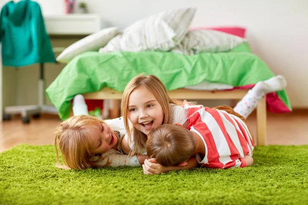 Crianças pequenas felizes deitadas no chão ou no tapete — Fotografia de Stock