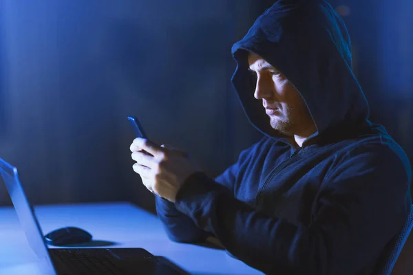 Hacker con portátil y smartphone en habitación oscura — Foto de Stock