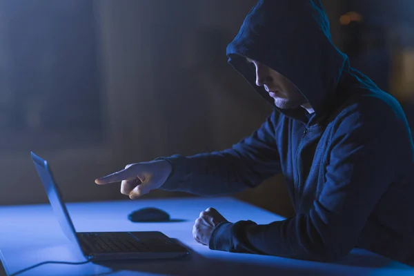 Hacker apuntando a la computadora portátil en la habitación oscura — Foto de Stock