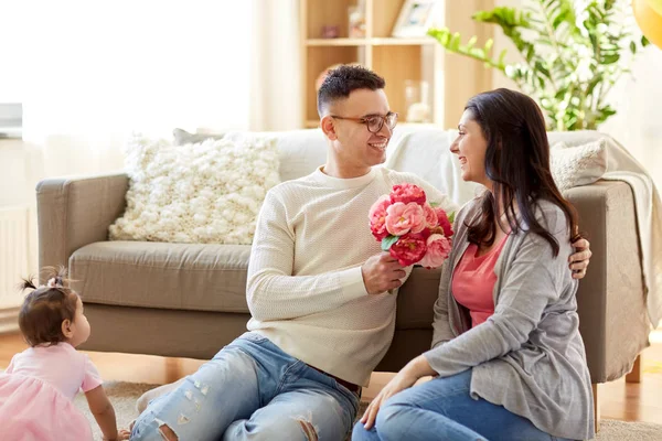 Happy husband giving flowers to his wife at home — Stock Photo, Image