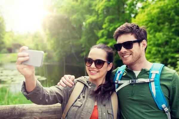 Couple with backpacks taking selfie by smartphone — Stock Photo, Image