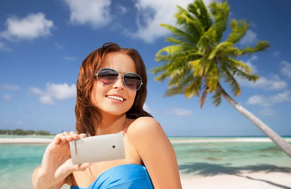 Женщина делает селфи на смартфоне на пляже — стоковое фото