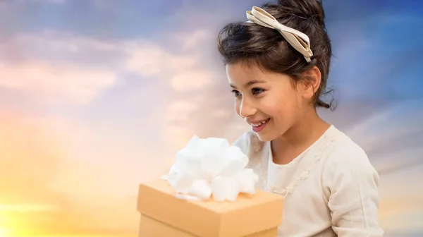 Happy girl with gift box over evening sky — Stock Photo, Image