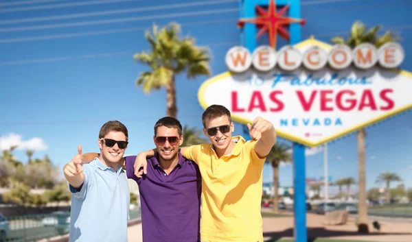 Група чоловіки, друзі обіймаються над Лас-Вегасі знак — стокове фото