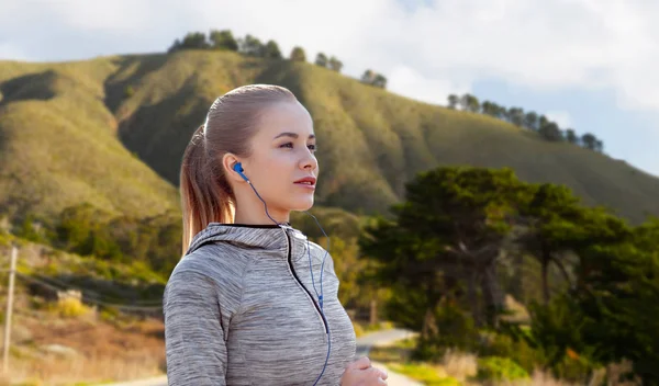 Vrouw met koptelefoon loopt over de heuvels van big sur — Stockfoto