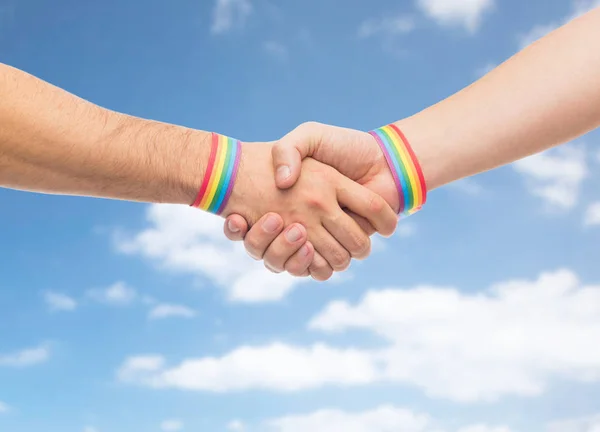 Mani con gay orgoglio braccialetti fare handshake — Foto Stock