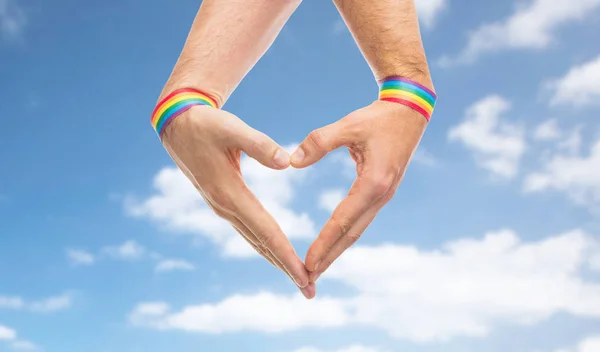 Les mains masculines avec gay pride bracelets montrant coeur — Photo