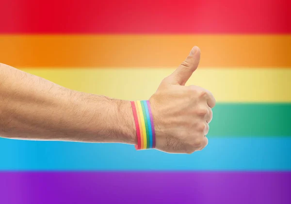 ゲイのプライド虹リストバンドと手は親指を示しています — ストック写真