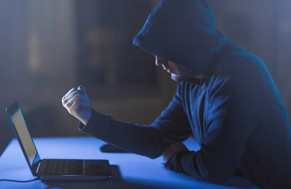 Хакер, що показує кулак ноутбуку в темній кімнаті — стокове фото