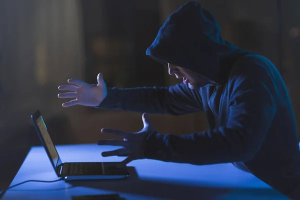 Boos hacker met laptop in de donkere kamer — Stockfoto
