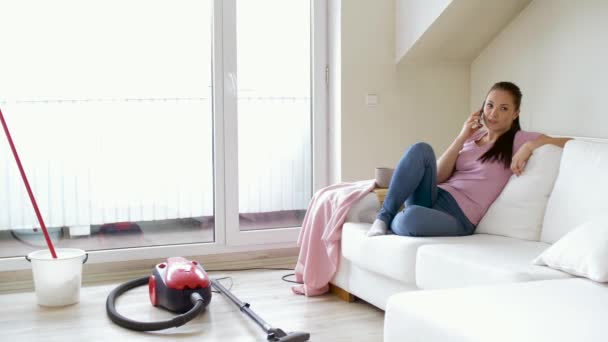 Woman calling by smartphone after cleaning home — Stock Video