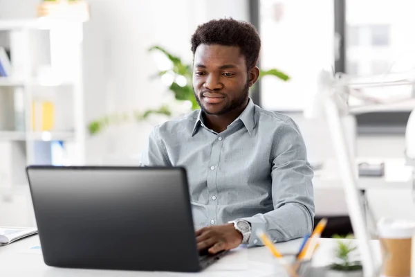 Empresário afro-americano com laptop no escritório — Fotografia de Stock