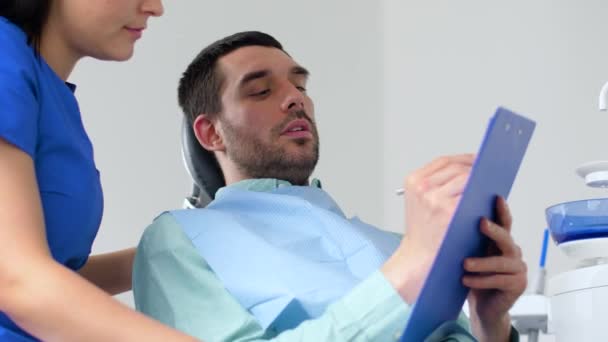 Dentista e paciente discutindo tratamento odontológico — Vídeo de Stock
