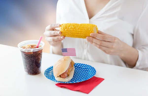 Woman eating corn with hot dog and cola — Stock Photo, Image