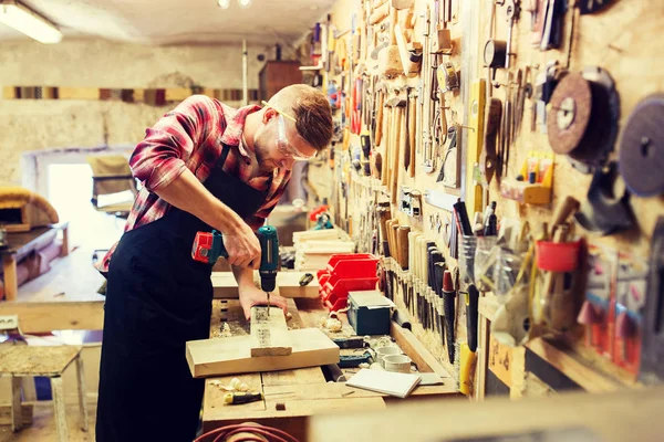 Carpenter with drill drilling plank at workshop — Stock Photo, Image