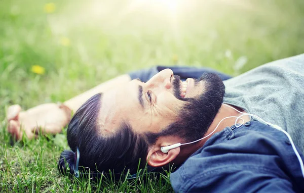 Человек с наушниками слушает музыку на траве — стоковое фото