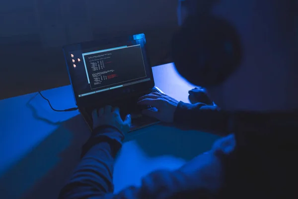 Hacker with coding on laptop computer in dark room — Stock Photo, Image