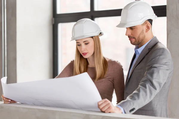 Architekten mit Blaupause und Helmen im Büro — Stockfoto