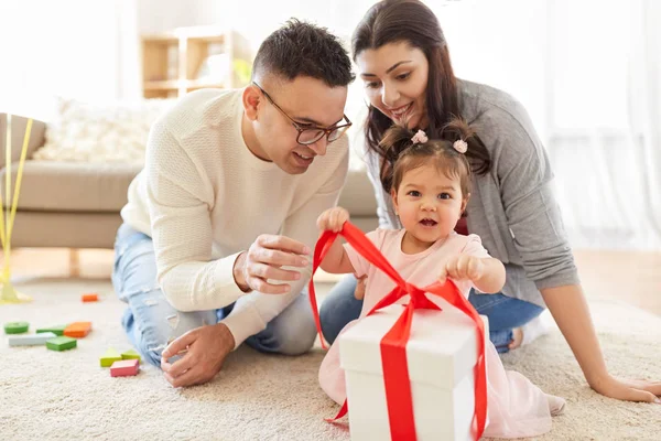 Baby flicka med födelsedagspresent och föräldrar hemma — Stockfoto