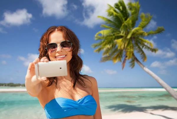 Женщина делает селфи на смартфоне на пляже — стоковое фото