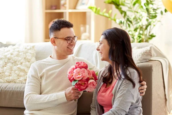 Marido feliz dando flores a su esposa en casa — Foto de Stock
