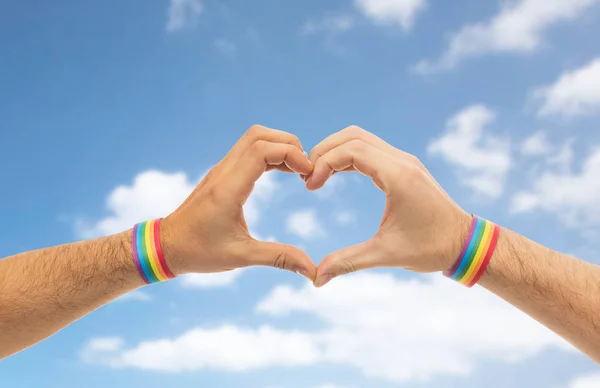 Manos masculinas con pulseras de orgullo gay mostrando el corazón — Foto de Stock