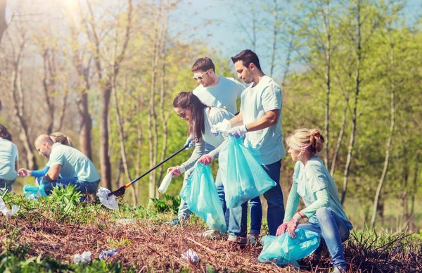 Vrijwilligers met vuilniszakken schoonmaak park — Stockfoto