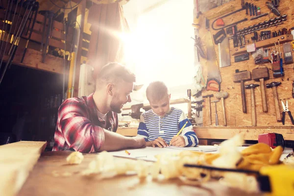 Счастливые отец и сын с чертежом в мастерской — стоковое фото