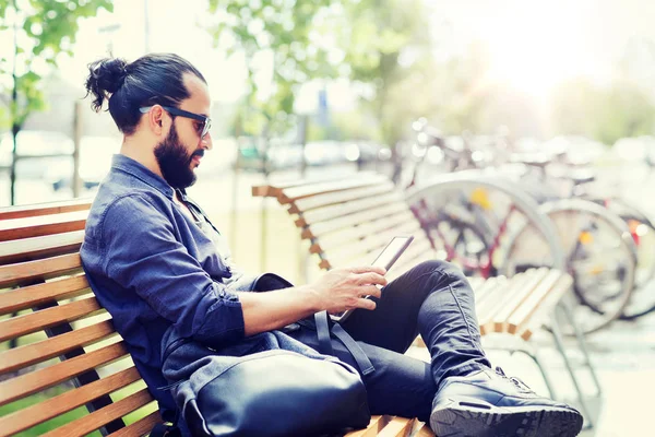 Чоловік з планшетним ПК сидить на вуличній лавці міста — стокове фото