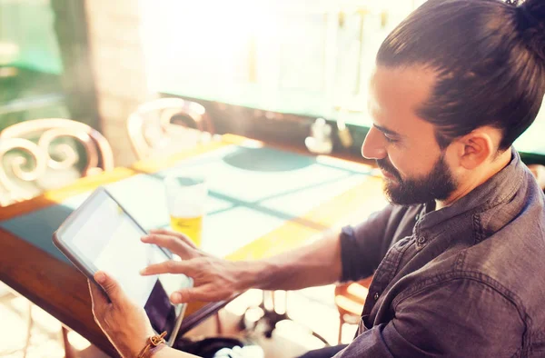 Man met tablet pc drinken bier bij bar of pub — Stockfoto