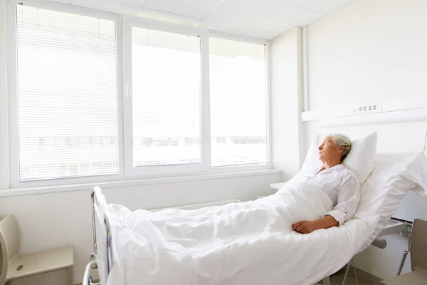 Triste mulher idosa deitada na cama na enfermaria do hospital — Fotografia de Stock