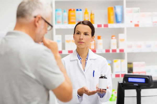 Boticario mostrando droga al hombre mayor en la farmacia — Foto de Stock