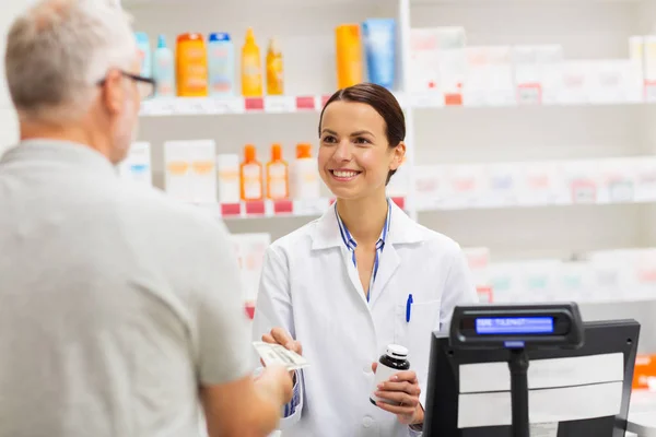 Apothecary selling drug to senior man at pharmacy — Stock Photo, Image