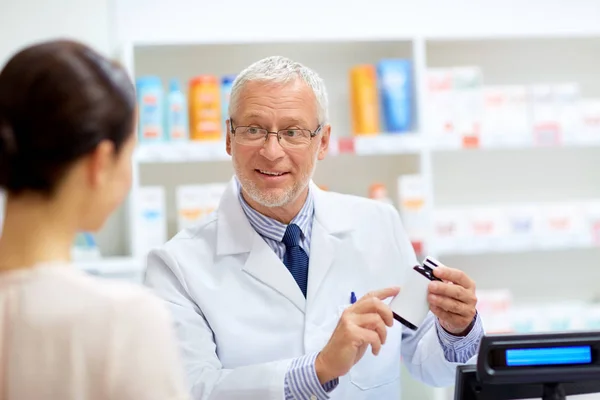 Apotheker met geneesmiddel en klant in de apotheek — Stockfoto