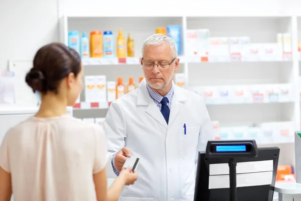 Lékárník s kreditní karty zákazníka v lékárně — Stock fotografie