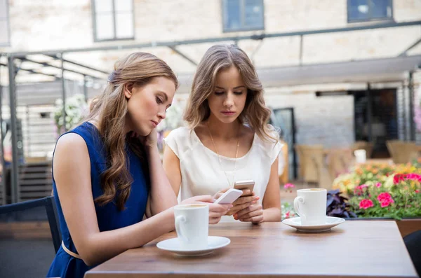 Mulheres jovens com smartphones e café no café — Fotografia de Stock