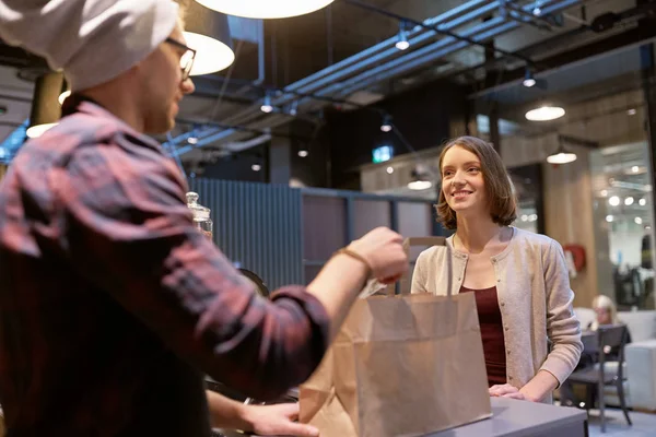 Vendedor dando saco de papel e dinheiro para a mulher no café — Fotografia de Stock