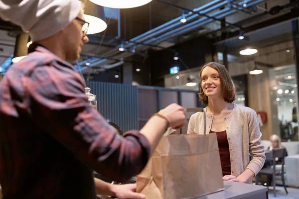 Verkäufer gibt Frau im Café Papiertüte und Geld — Stockfoto