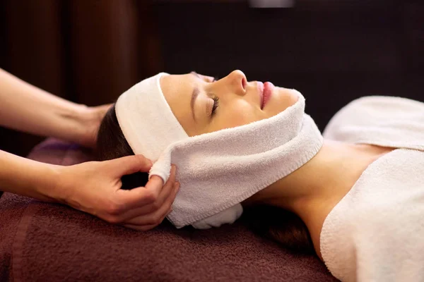 Mujer teniendo masaje facial con toalla en el spa —  Fotos de Stock