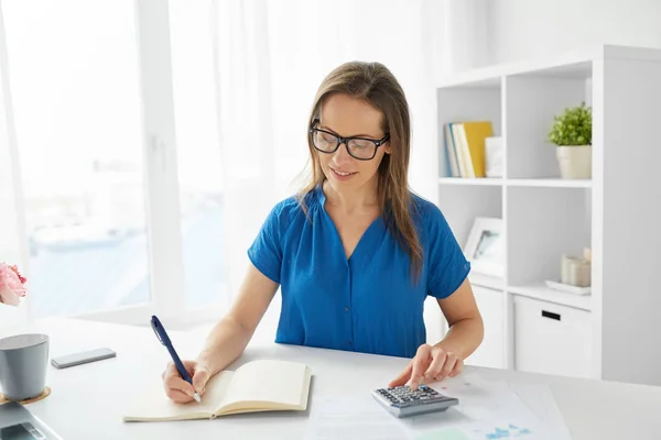 Mujer feliz con calculadora y portátil en la oficina — Foto de Stock
