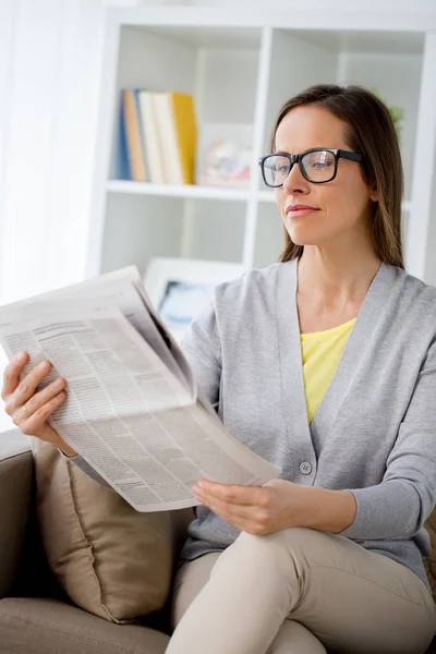 Γυναίκα με γυαλιά ανάγνωσης εφημερίδων στο σπίτι — Φωτογραφία Αρχείου
