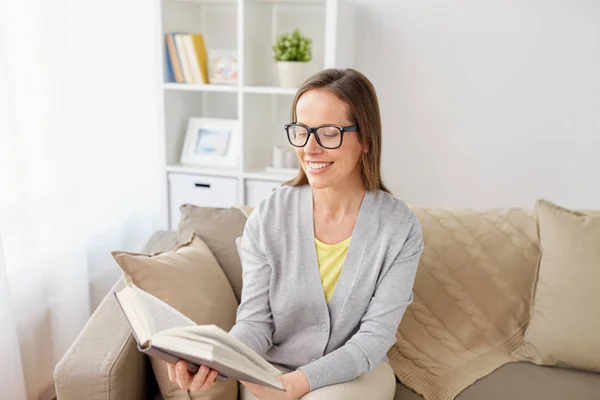 Glückliche Frau mit Brille liest Buch zu Hause — Stockfoto