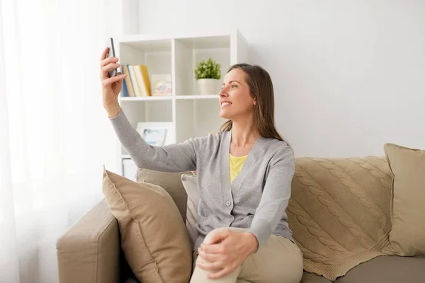幸福的女人，用智能手机在家里拿自拍照 — 图库照片