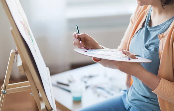 Artist with palette and brush painting at studio — Stock Photo, Image